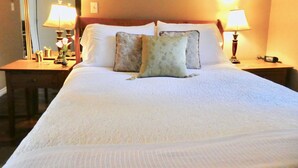 A neatly made bed with white linens and two decorative pillows, flanked by two bedside tables with lamps. - Belle Neige Suites- Whistler (Whistler)