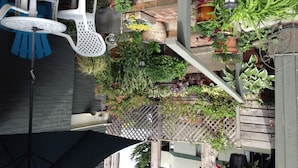 Ein Dachgarten mit verschiedenen Blumentöpfen, einem Holzzaun und Gartenmöbeln.