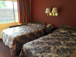 A hotel room with two beds, a window with curtains, a wall-mounted lamp, and a bedside telephone. - Super 7 Inn (Little Rock)