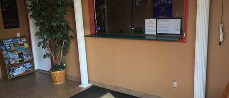 A reception area with a bulletin board, a potted plant, and a 'Super 7' sign.