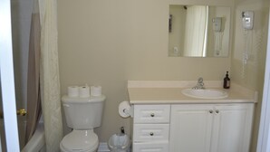 A bathroom with a toilet, sink, mirror, and shower curtain. - Downtown Whitby Furnished Homes (Whitby)