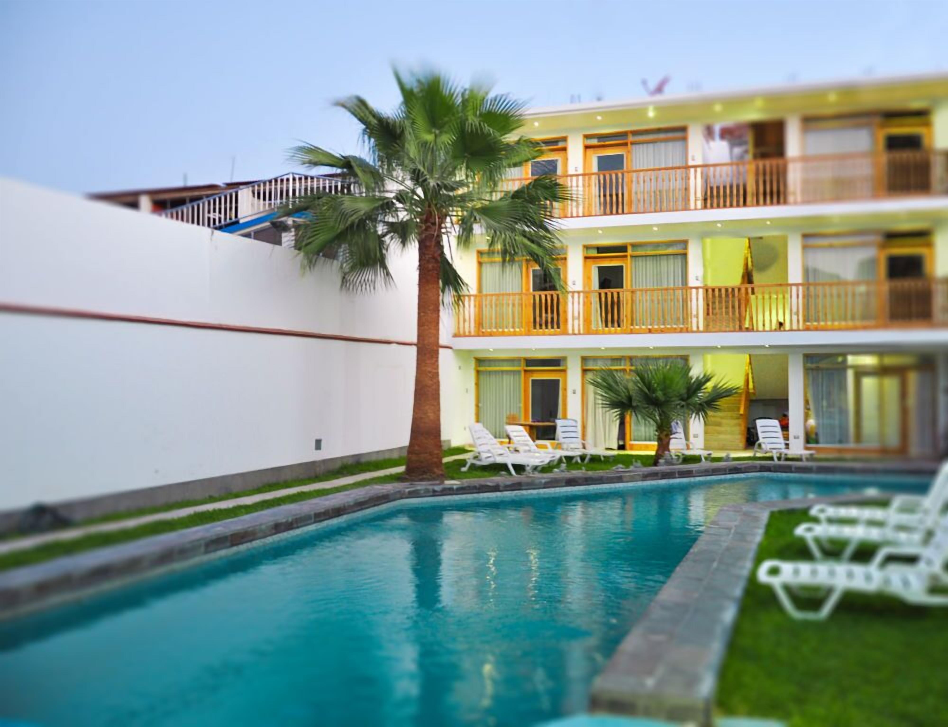 Un hotel con piscina, paredes blancas y balcones con barandillas de madera.