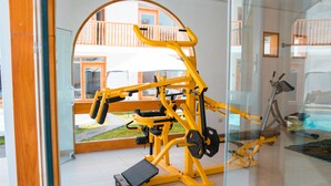 A gym with exercise equipment, a glass wall, and a view of a balcony.