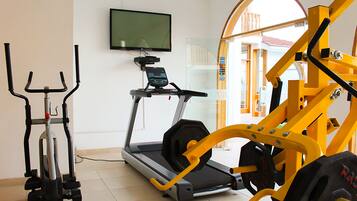 A home gym with a treadmill, elliptical, and weight machine.