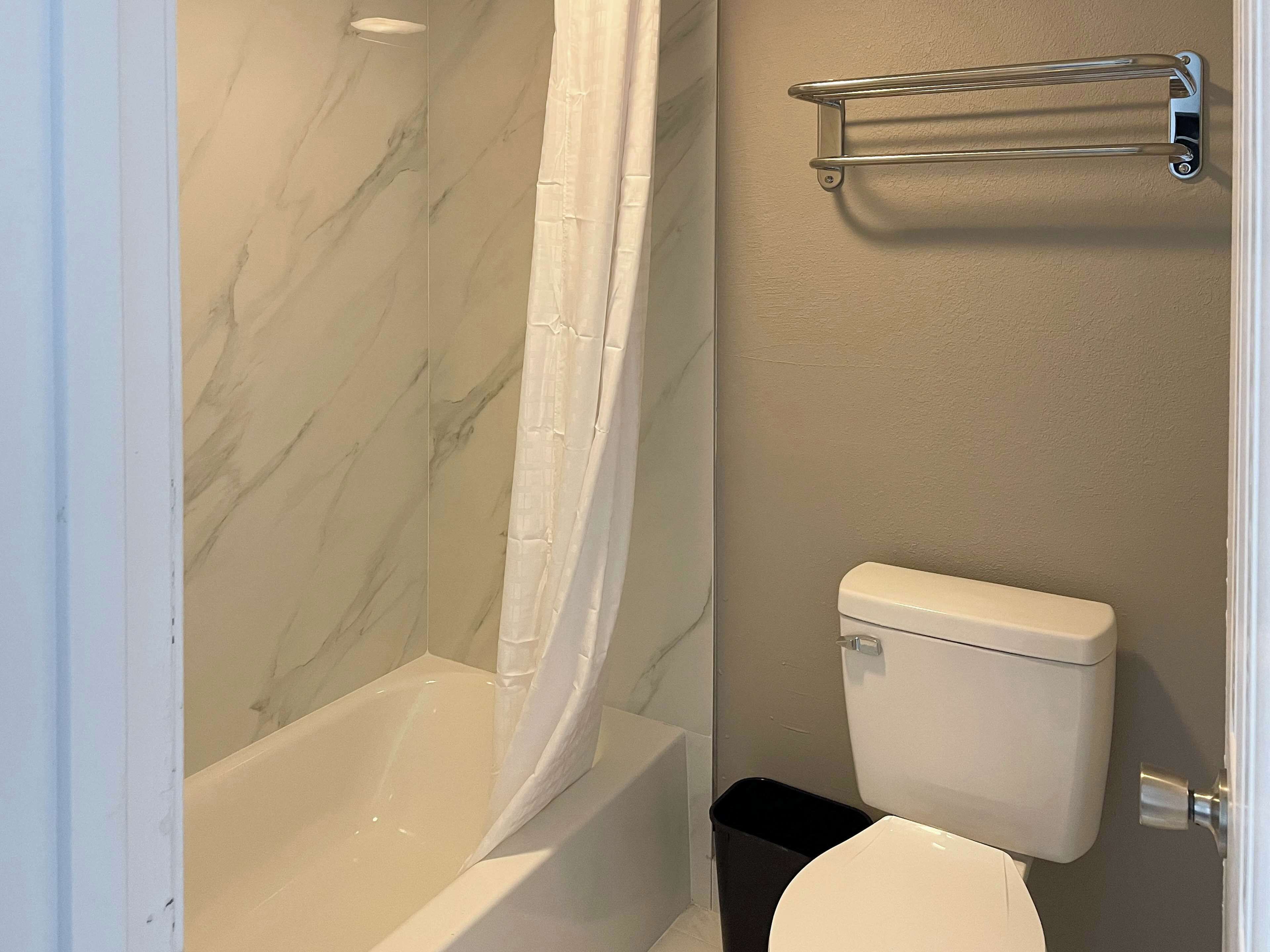 Een badkamer met een bad, toilet en douchegordijn.