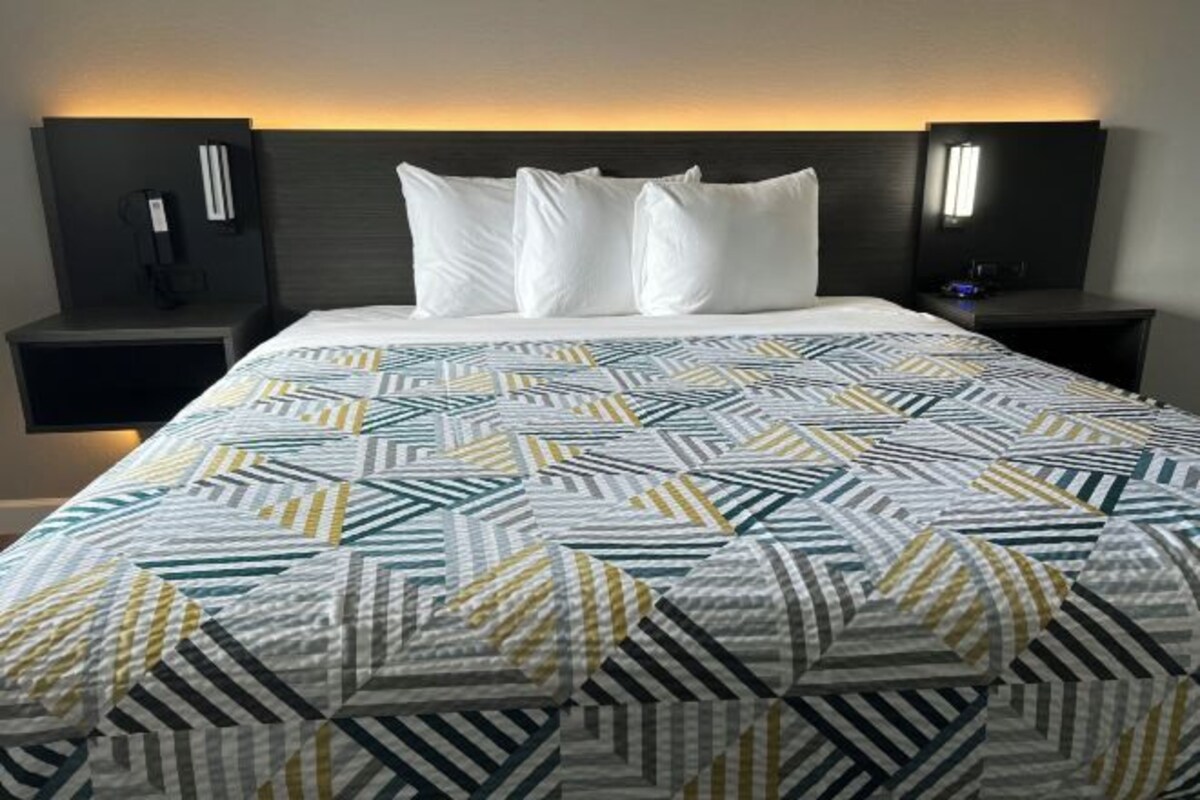 Una habitación de hotel con una cama, dos mesitas de noche y un cabecero.