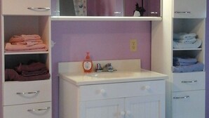 A bathroom with white cabinets, a sink, and a mirror. - Attwood Creek Ranch (Lone Butte)