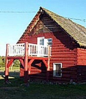 A red wooden barn with a porch and a small window.