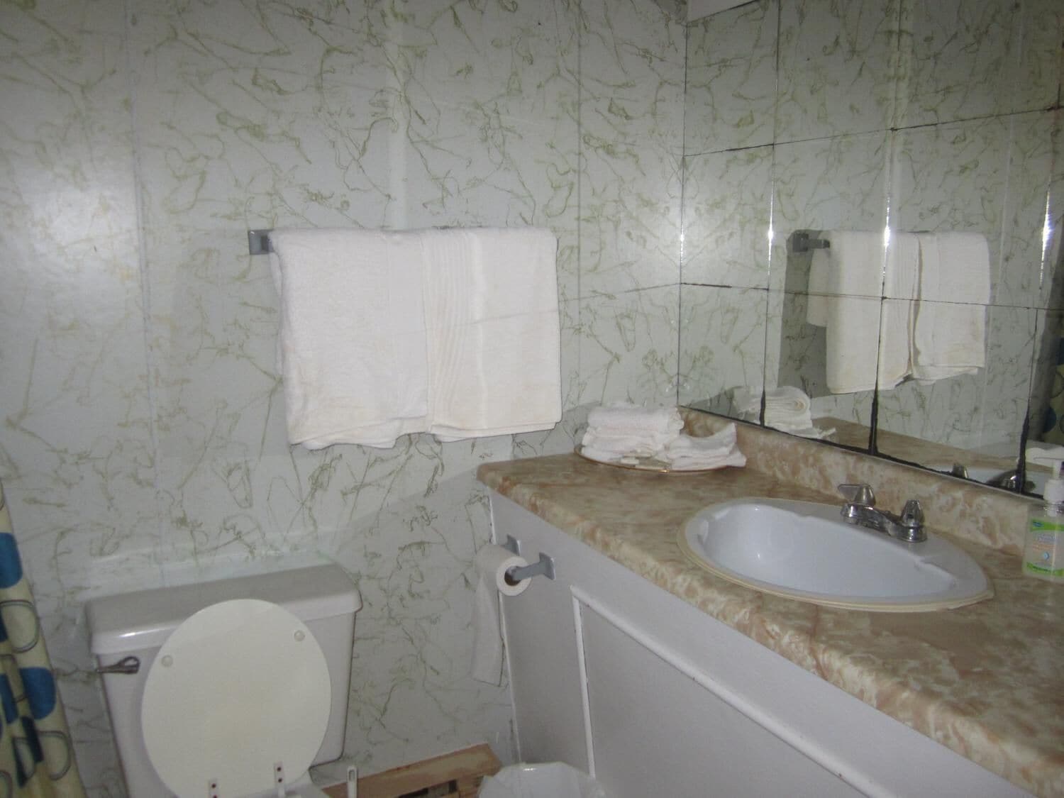 A bathroom with a toilet, sink, and mirror.