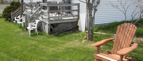 Una terraza de madera con mobiliario exterior, una escalera que lleva a una casa y un letrero que dice 'MOT'.