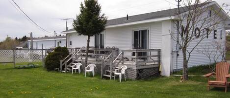 Ein Motel mit überdachter Terrasse, Außenbestuhlung und einem kleinen Baum.