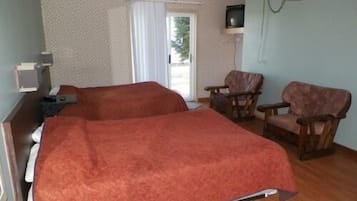 A room with two beds, a chair, a desk, and a television.