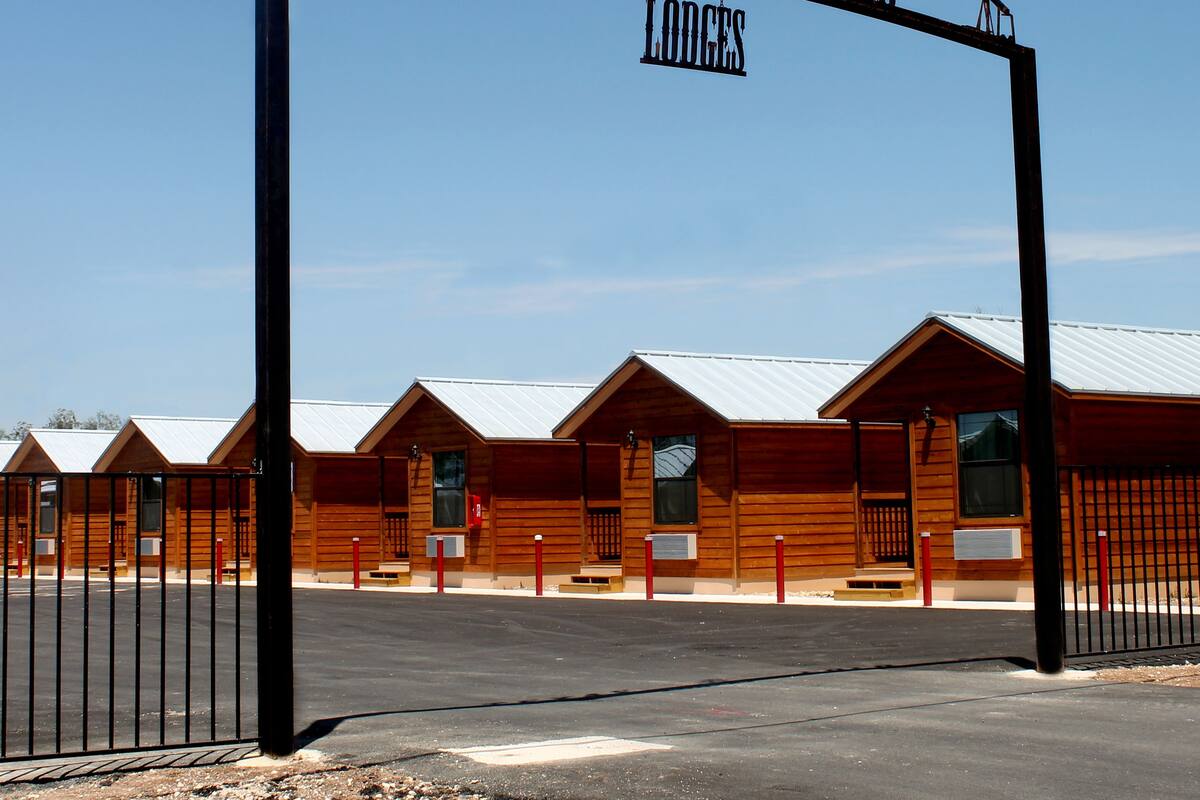 Una cabaña de madera con una puerta de metal que dice "Texas Gold Lodges".