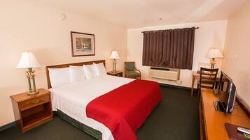 A hotel room with a bed, two bedside tables, a desk with a chair, a television, and a window with curtains.