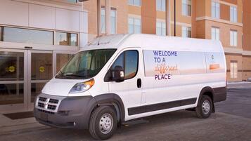 A white van parked in front of a building with a sign that reads "Welcome to a different place."
