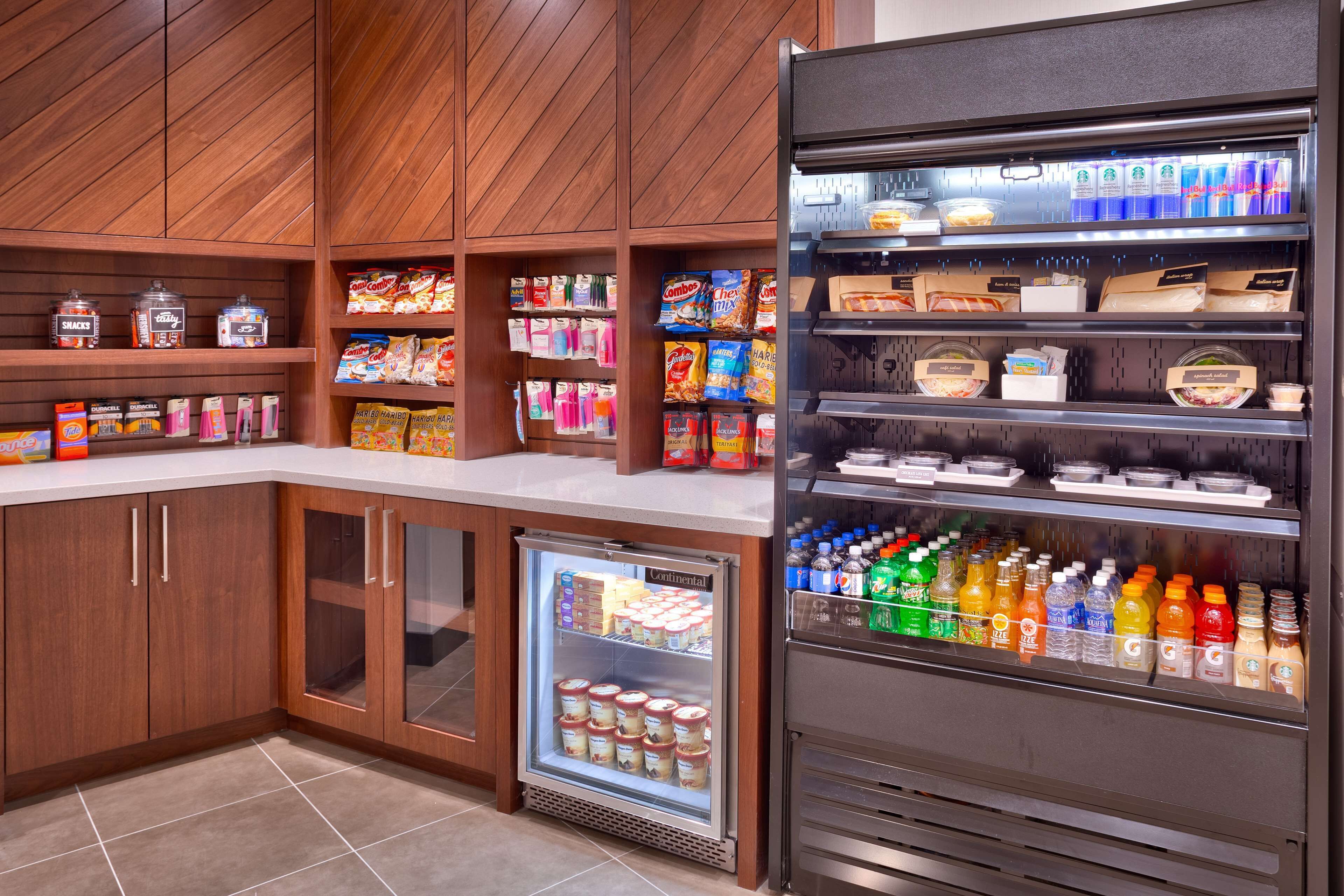 Un espace de restauration en libre-service proposant une variété de boissons, réfrigérées ou non, ainsi que des en-cas et des condiments.