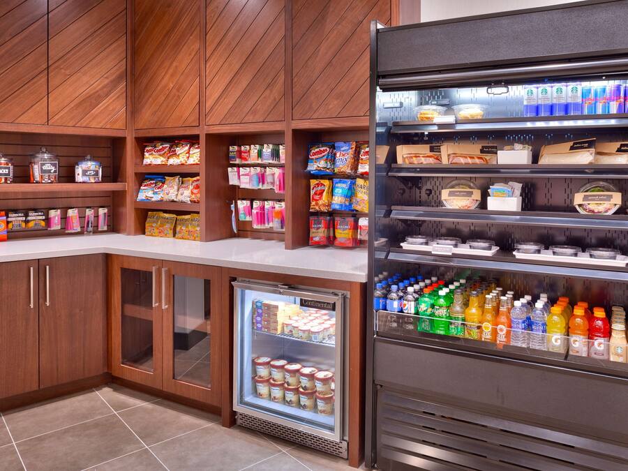 A self-service food station with refrigerated and non-refrigerated beverage options, snacks, and condiments.