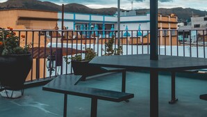 A rooftop terrace with a metal umbrella, seating, and potted plants. - Hotel Aurora (Oaxaca)