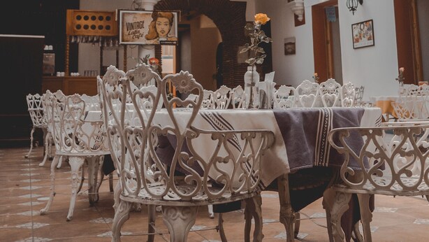 A dining area with ornate white chairs and tables, decorated with colorful paper lanterns. - Hotel Aurora (Oaxaca)
