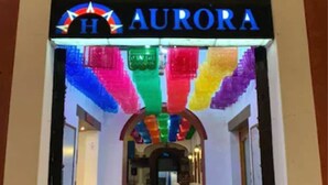 A hotel entrance with a sign reading "AURORA" and colorful hanging decorations. - Hotel Aurora (Oaxaca)