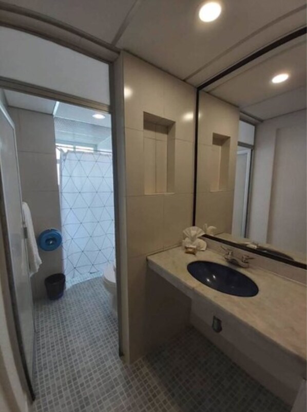 Un baño moderno con un espejo grande, un lavabo y un inodoro.