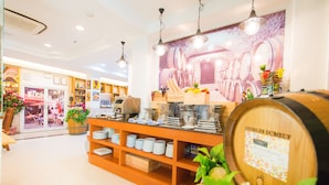 Interior de un restaurante con una exhibición de barriles de vino, estantes con platos y un mural de barriles de vino.