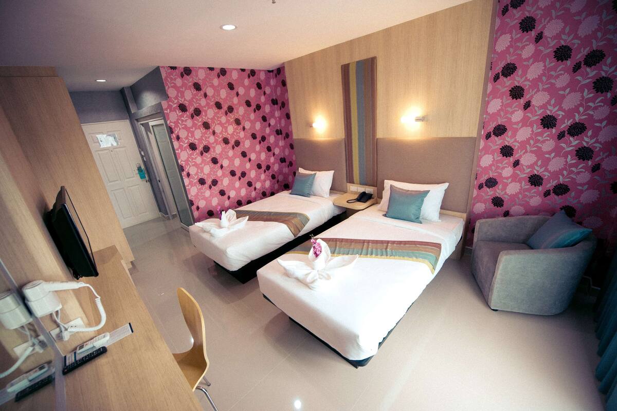 Habitación de hotel con dos camas, un escritorio con teléfono y una silla.