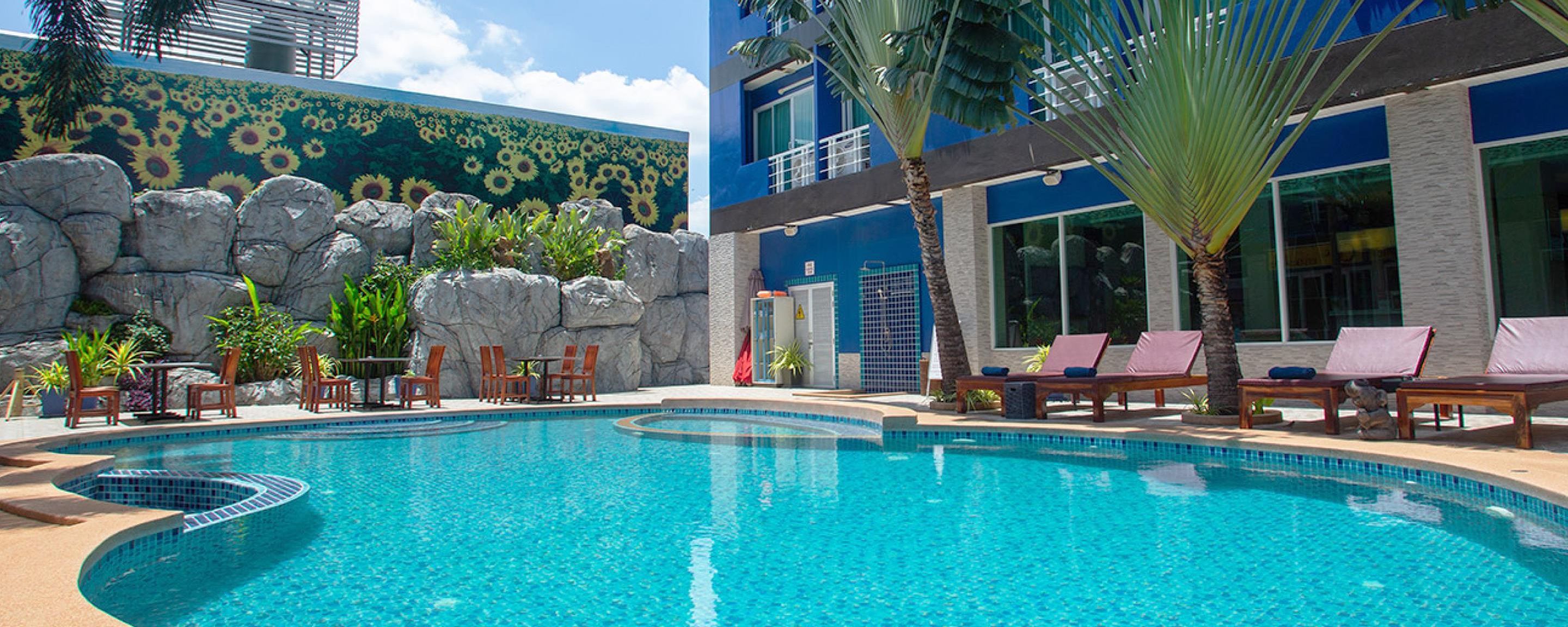 A swimming pool with lounge chairs and a mural of sunflowers on the wall.