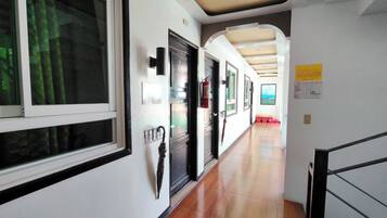 Un pasillo con piso de madera, un extintor y un cartel en la pared.