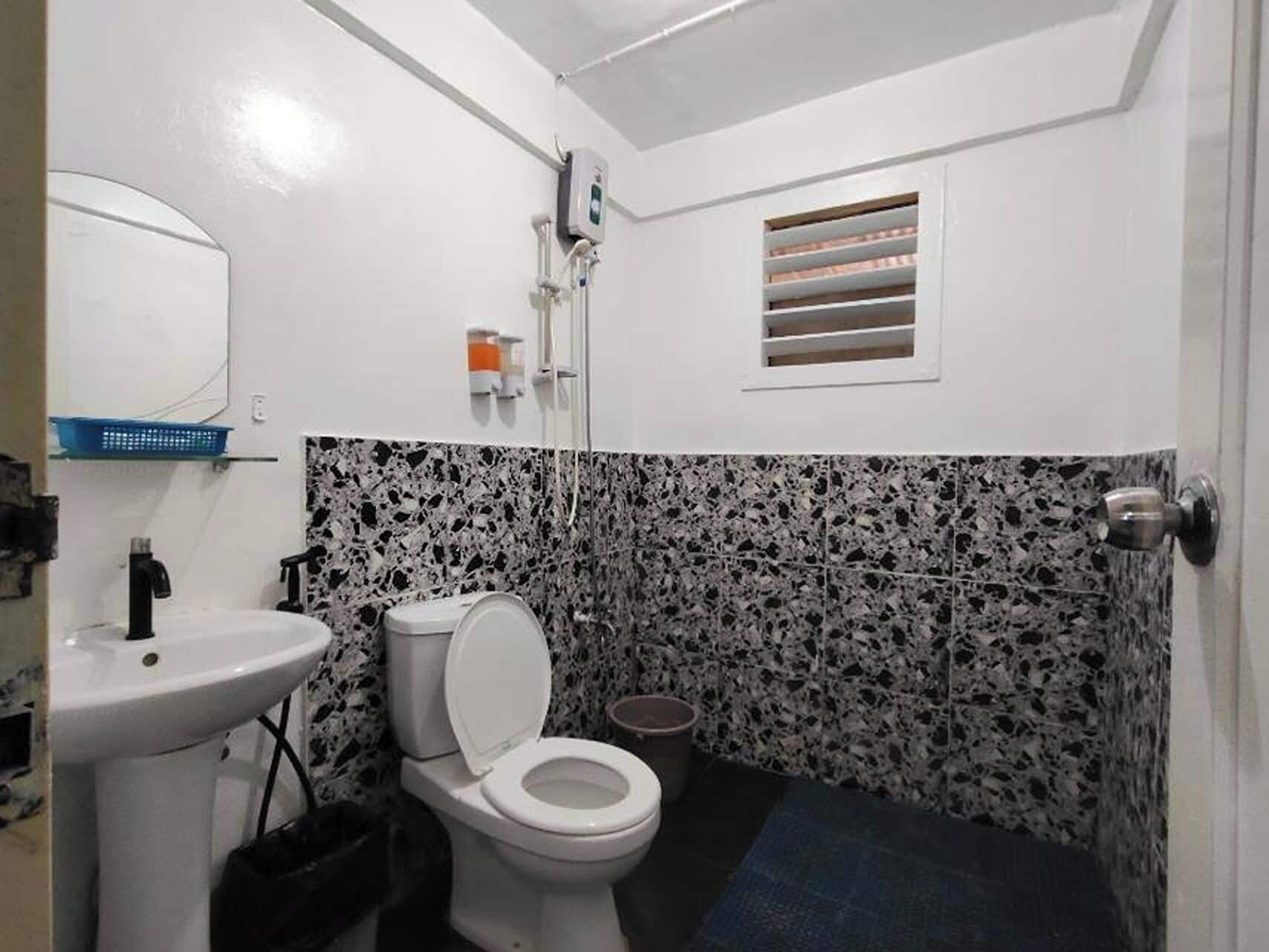 A compact bathroom with a white sink, toilet, and shower.