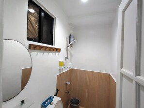 A bathroom with a toilet, sink, mirror, shower, and a window. - Joaquinn's Bed and Breakfast El Nido City near Beach (El Nido)