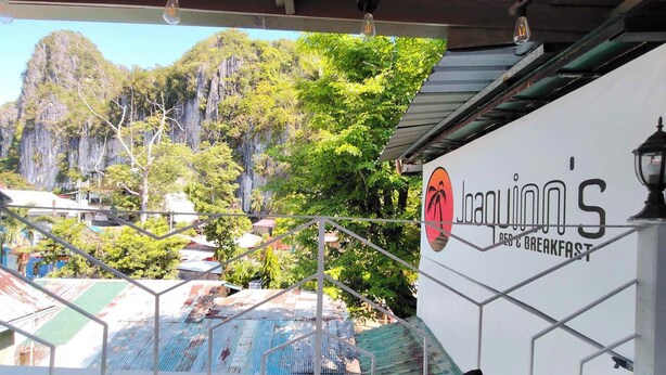 Un restaurante llamado 'Joapinn's' con vistas a un paisaje montañoso y una barandilla metálica.