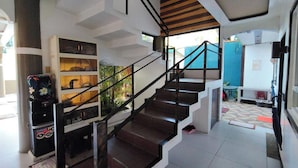 Un interior moderno con una escalera, estanterías empotradas y vistas al exterior.