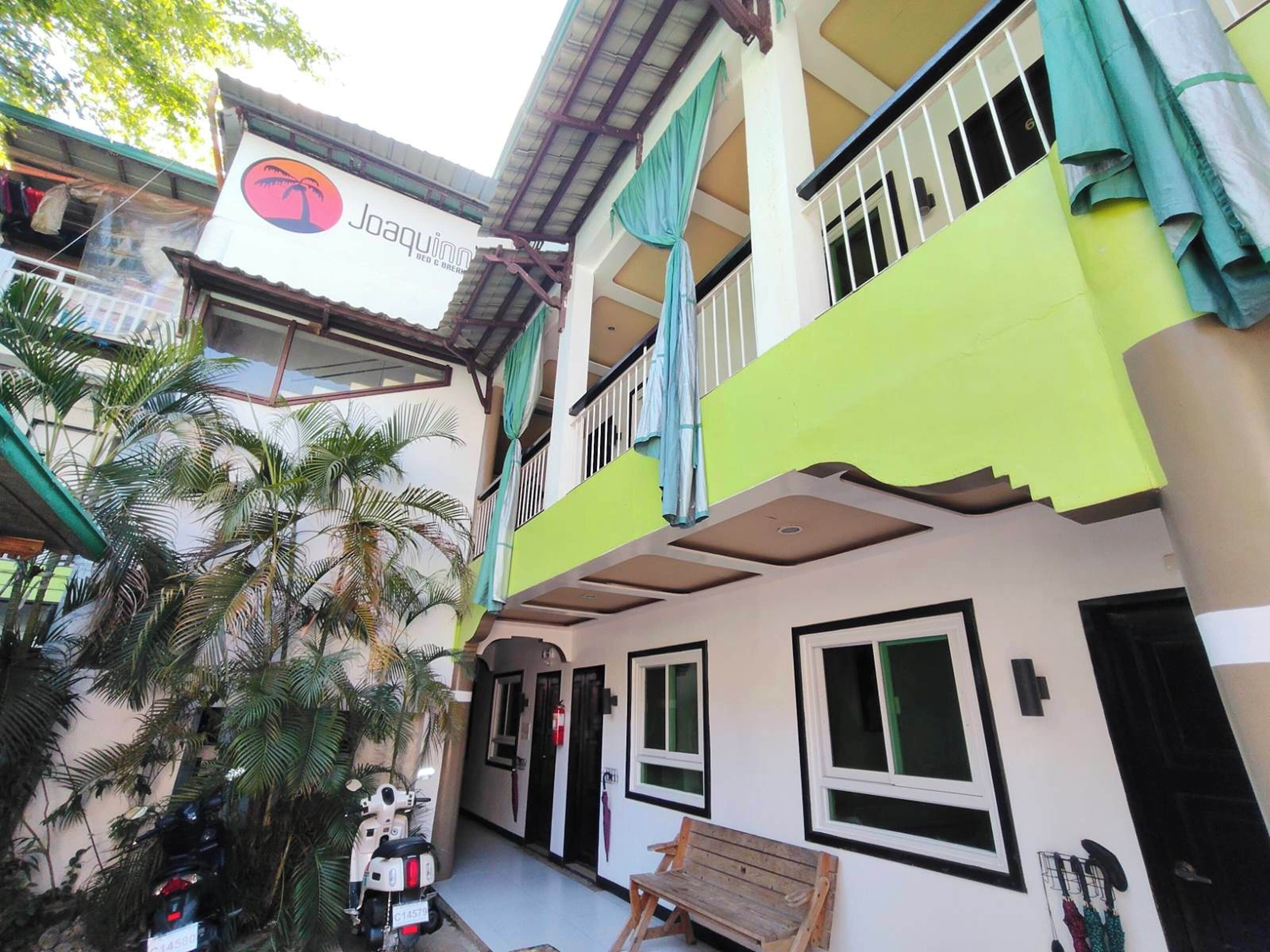 A multi-story building with a sign for 'Joaquinn' and a balcony with a view.
