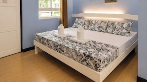 Un dormitorio con una cama, una ventana con cortinas y dos cuadros colgados en la pared.