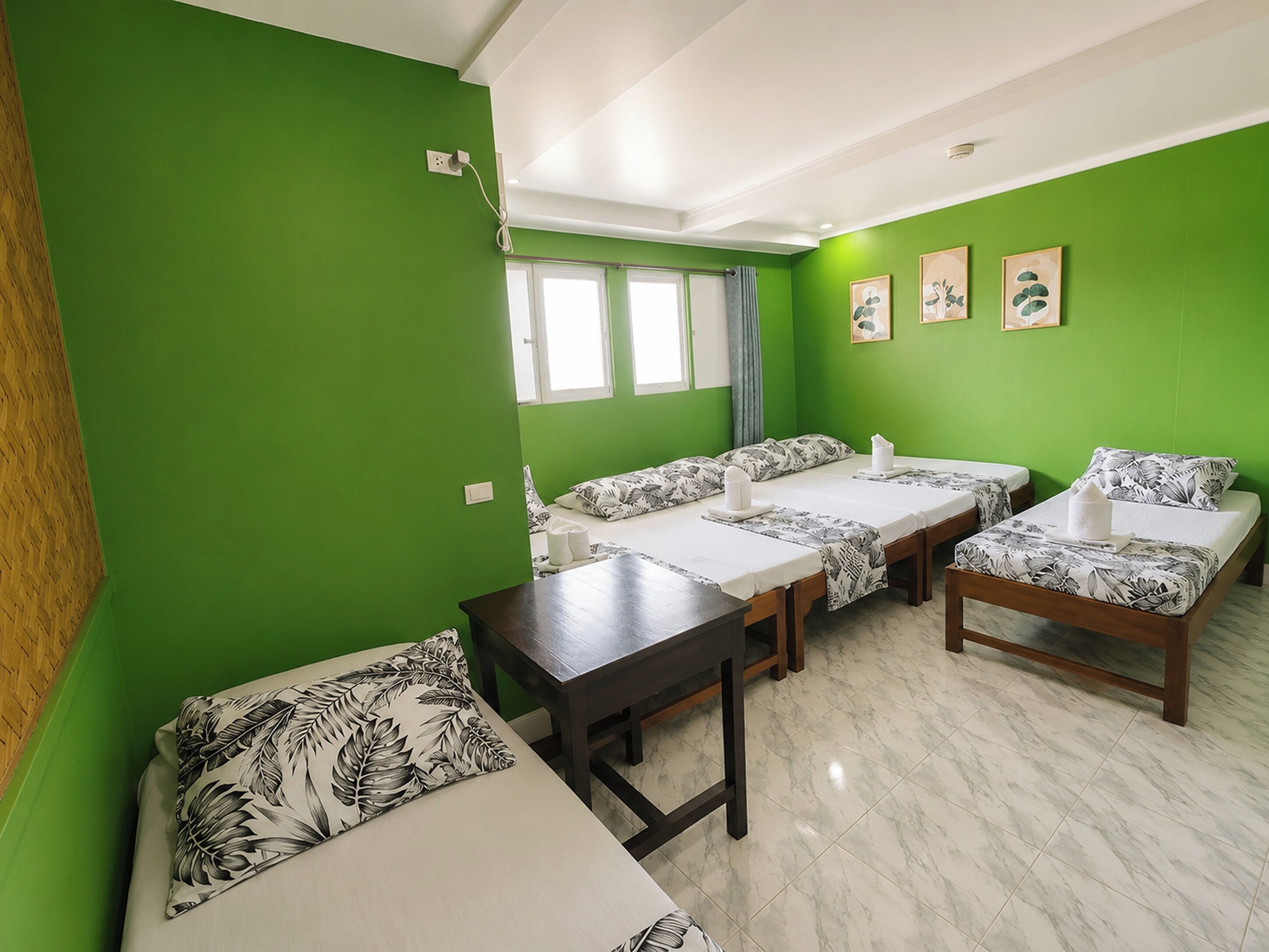 A room with green walls, two single beds, a sofa, and a table.