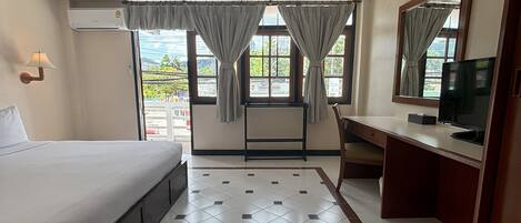 A hotel room with a bed, a desk, a TV, and a window with curtains.