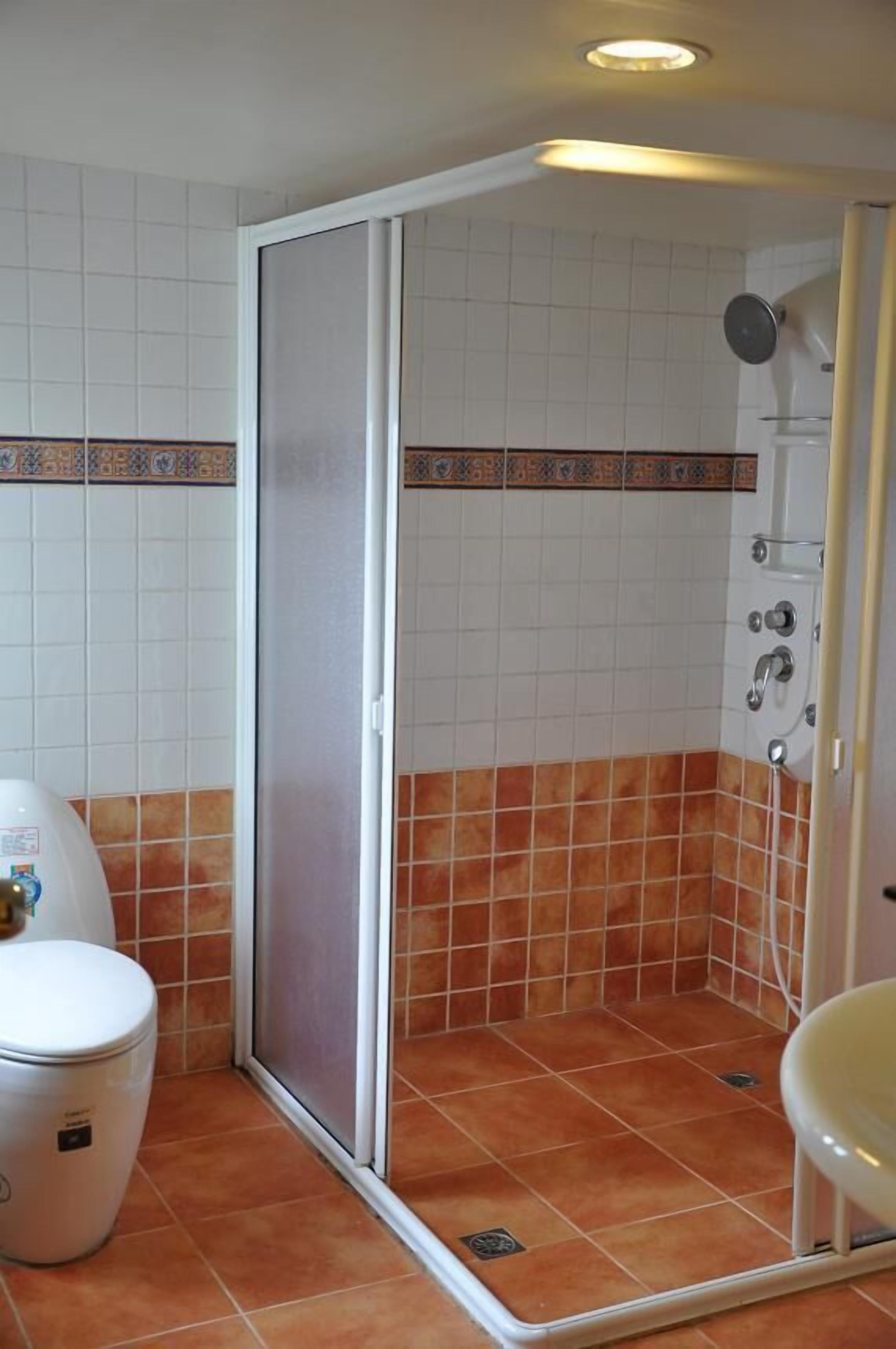 Une salle de bain avec douche, toilettes et lavabo.