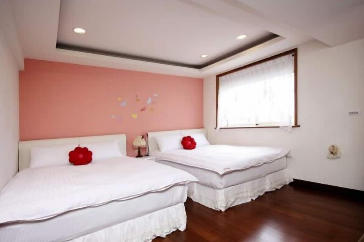 Ein Hotelzimmer mit zwei Betten, einer Wand in Rosa und einem großen Fenster.