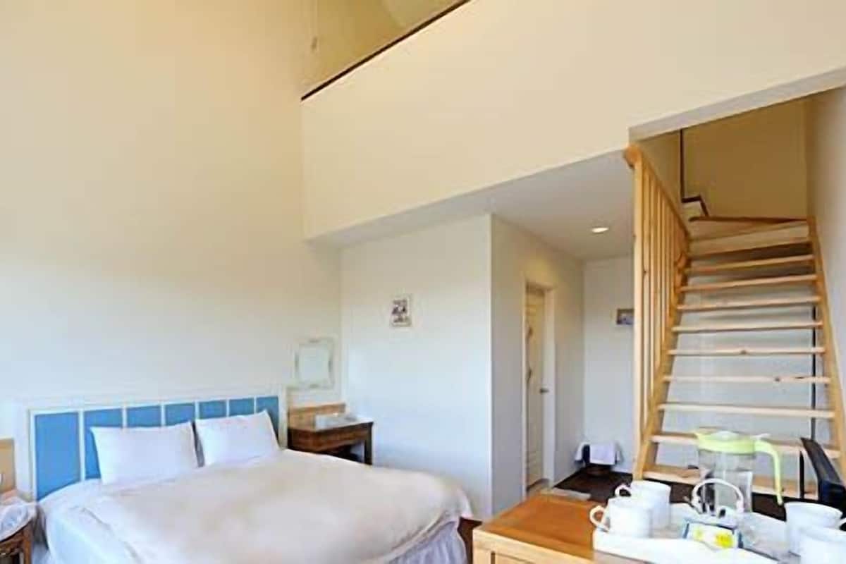 Ein Hotelzimmer mit einem Bett, einem Nachttisch und einer Holztreppe.