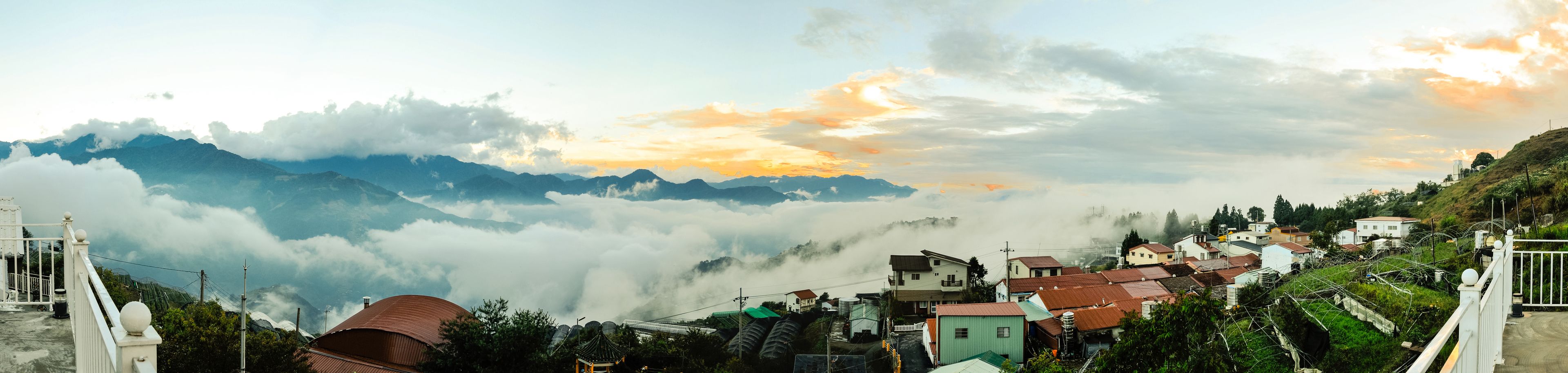 Un pueblo en la montaña con casas tradicionales y una vista de las nubes abajo.