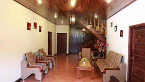 Amplia sala de estar con techo de madera, una escalera y un conjunto de sofás y sillones.