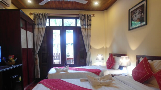 Habitación de hotel con dos camas, televisión, escritorio y ventana con cortinas.