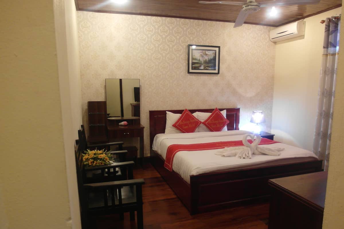 A hotel room with a bed, bedside table, mirror, and a small desk with a chair.