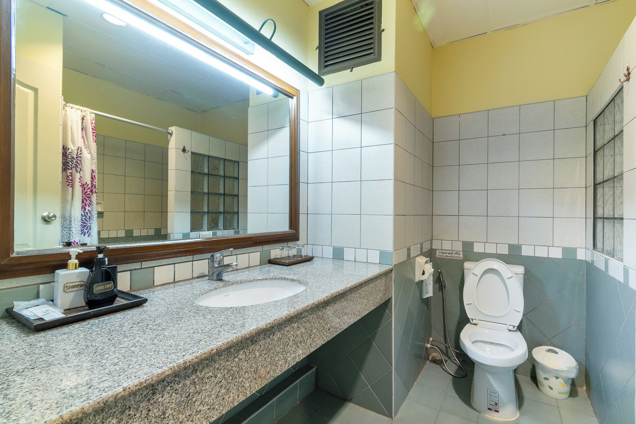 Une salle de bain avec un comptoir en granit, un lavabo, un miroir, des toilettes et un espace douche.
