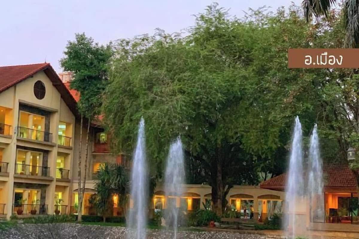 A multi-story hotel with a red roof, balconies, and a fountain in the foreground.