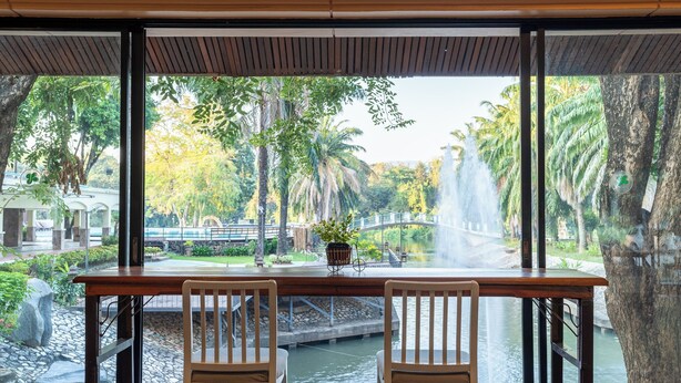 A table with two chairs facing a view of a water feature and a bridge.