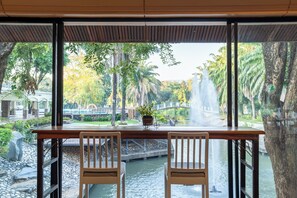 A table with two chairs facing a view of a water feature and a bridge. - Pung-waan Resort & Spa Kanchanaburi (Kanchanaburi)