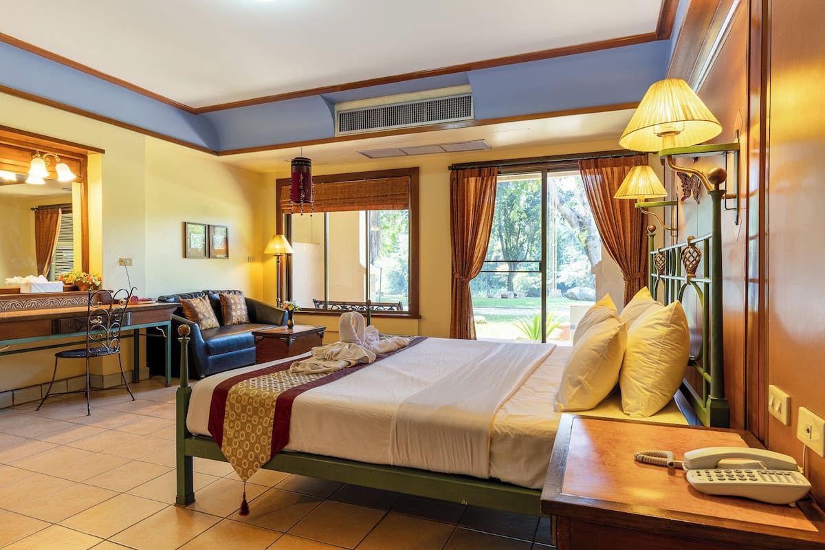 A hotel room with a bed, bedside table, lamp, and a desk with a chair.