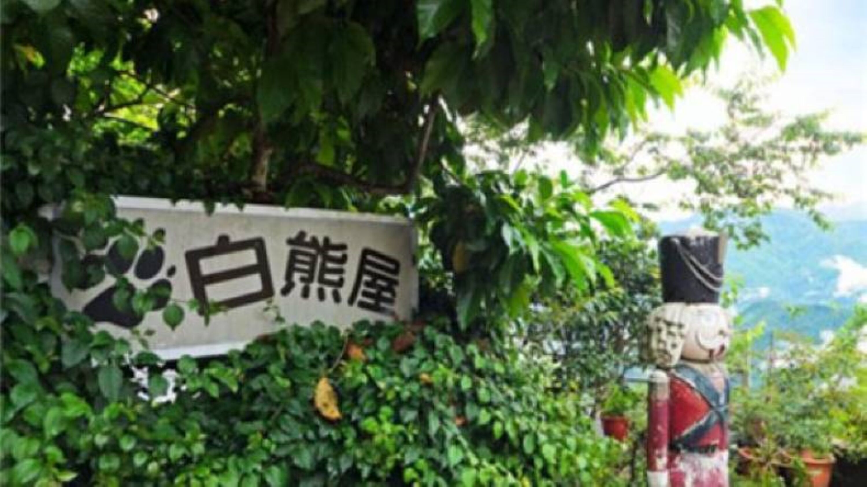 A sign with Chinese characters, surrounded by lush greenery.